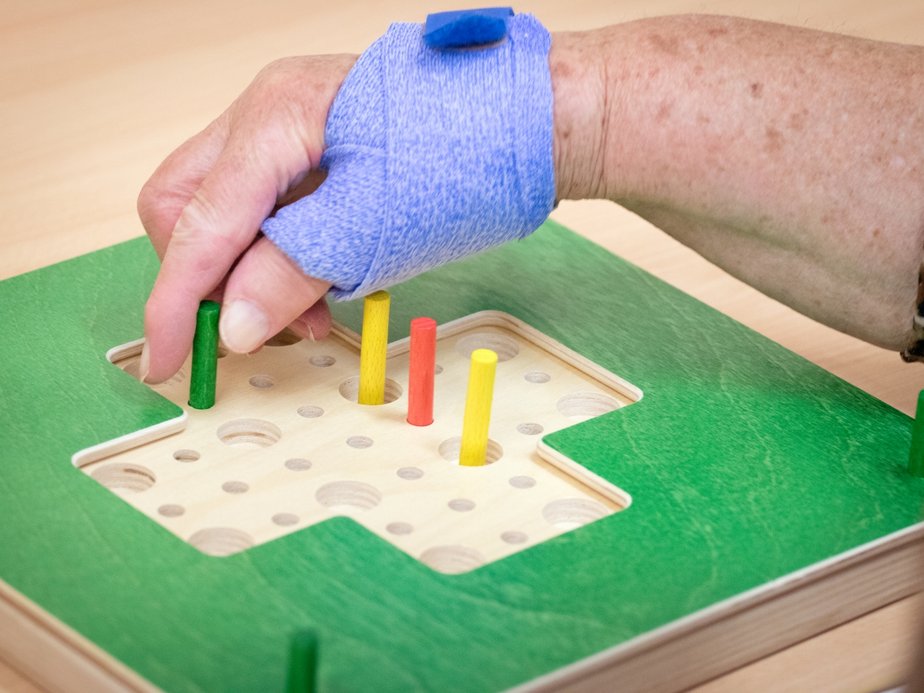 Eine Bewohnerin hält Holzstäbchen in der Hand.
