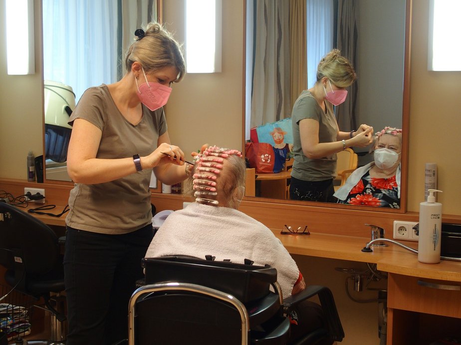 Friseurin frisiert Bewohnerin.